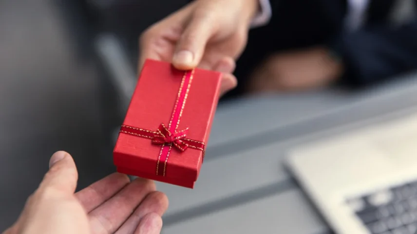 Uma pessoa entregando um pacote de presente vermelho para outra pessoa.