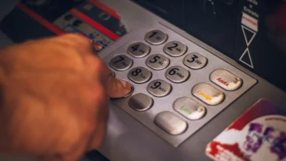 Mão digitando números em caixa eletrônico de banco.