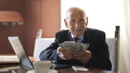 Homem idoso segurando notas de dinheiro.