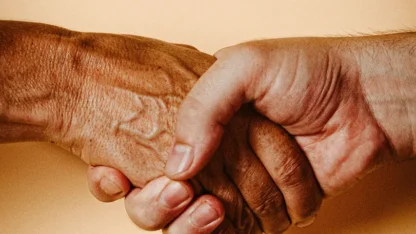 Duas mãos, uma de pessoa mais velha e outra de pessoa mais nova, segurando uma à outra.