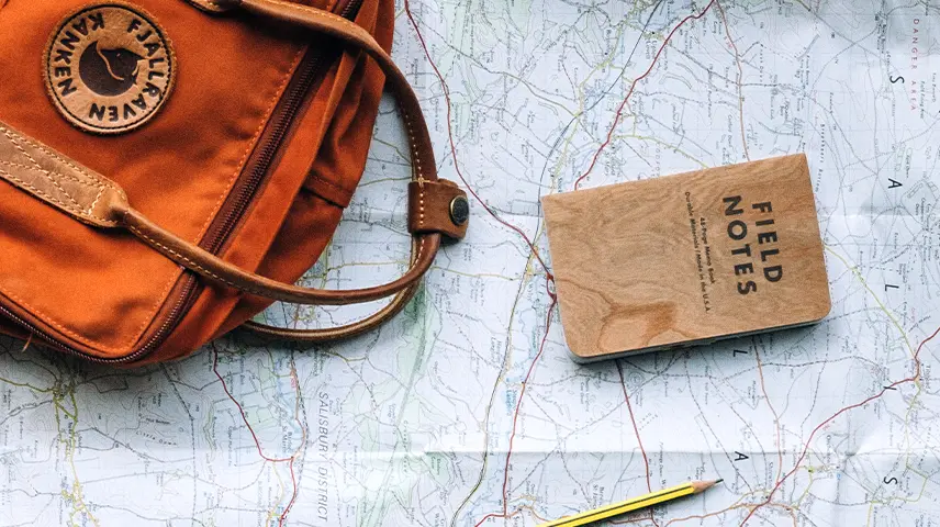 Mala de mão sobre um mapa, com um passaporte ao lado.